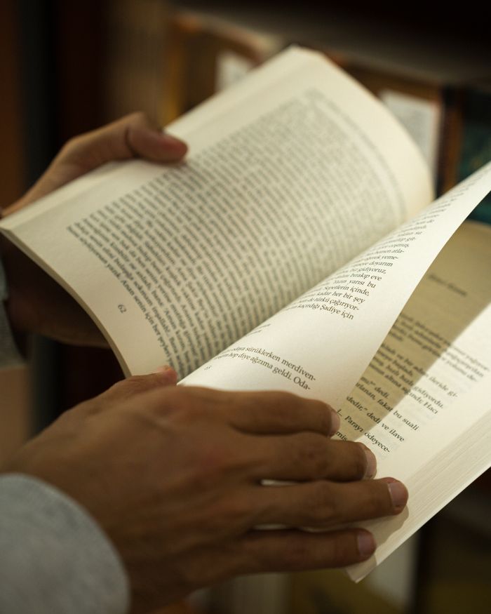 why-choose-us Close-up of hands flipping pages of a book in a library in Ankara, Türkiye.